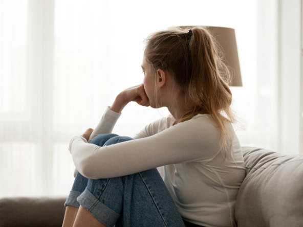 Upset-anxious-woman-sitting-on-couch-alone-at-home_crop